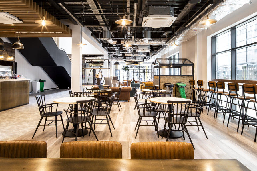 An empty restaurant with tables and industrial lighting by Industville