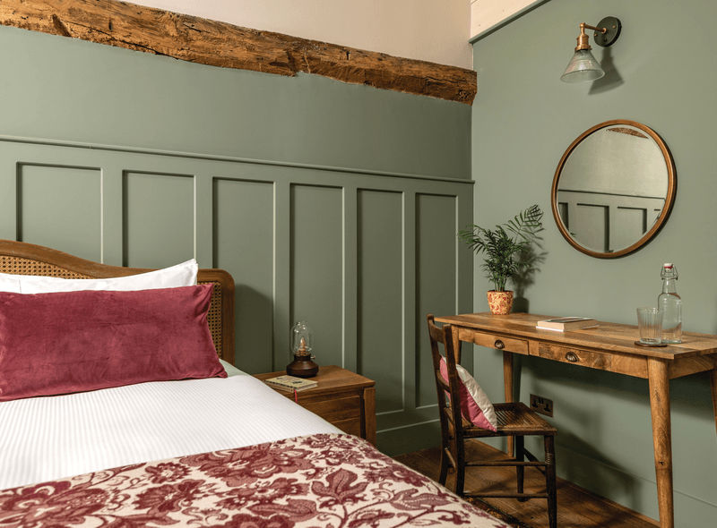 A bedroom decorated in sage green, white and red