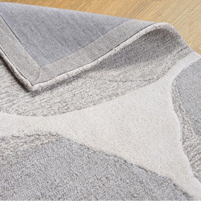 A hand-tufted wool rug with a beige and gray color scheme, showing the texture and quality of the wool.