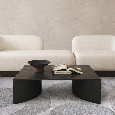Modern living room with a black coffee table, white sofa, and decorative bowl.