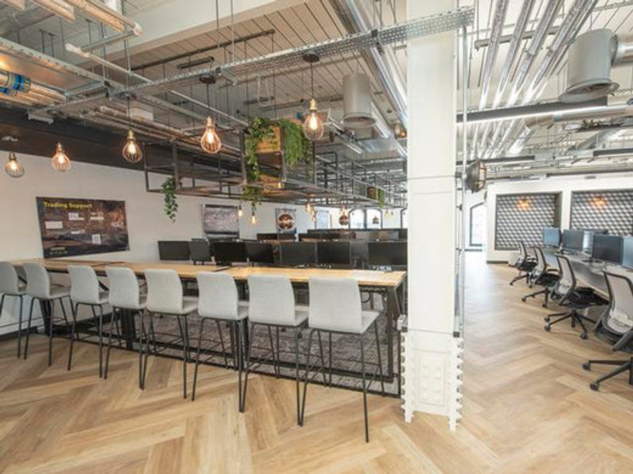 An industrial office space decorated with wire cage pendants. 