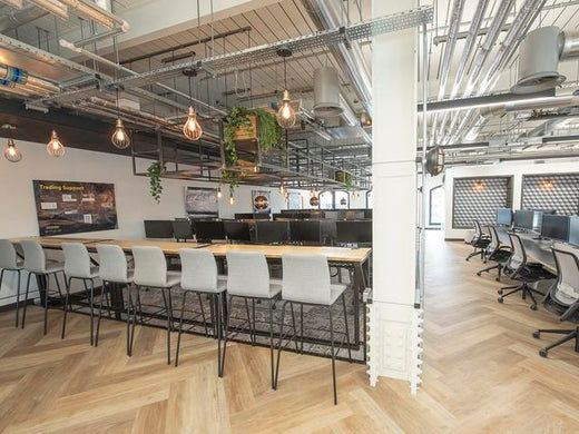 An industrial office space decorated with wire cage pendants. 