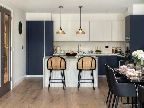 Two glass pendant lights hanging over a kitchen island and bar stools
