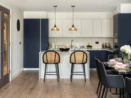Two glass pendant lights hanging over a kitchen island and bar stools