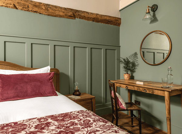 A bedroom decorated in sage green, white and red