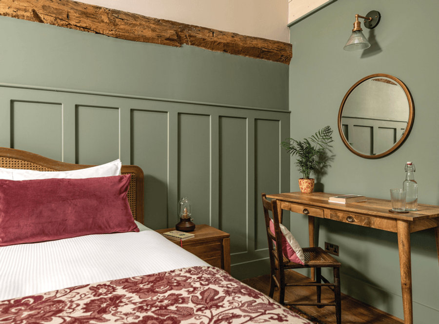 A bedroom decorated in sage green, white and red