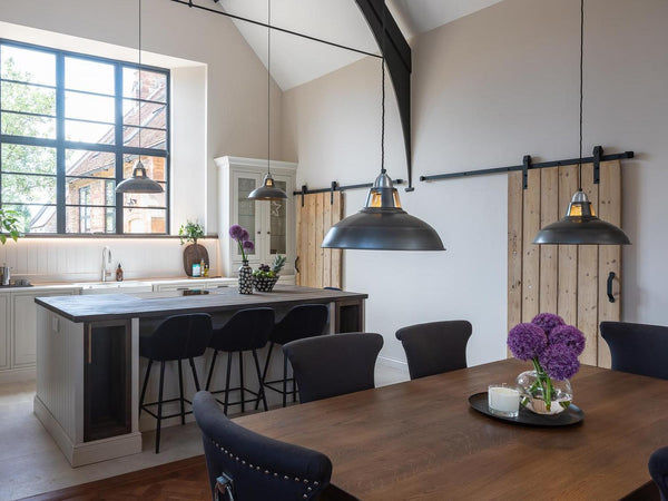 Rustic style open plan kitchen and dining room with neutral palette and pewter factory style pendants