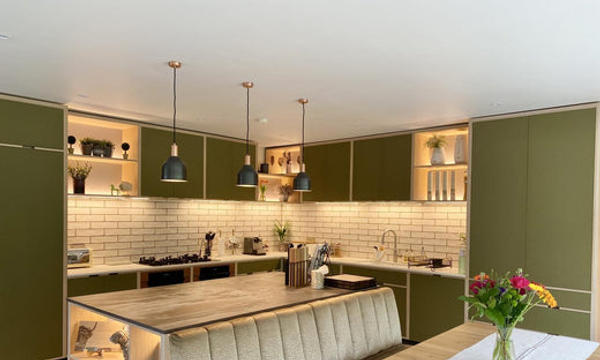 A green kitchen illuminated with warm white light