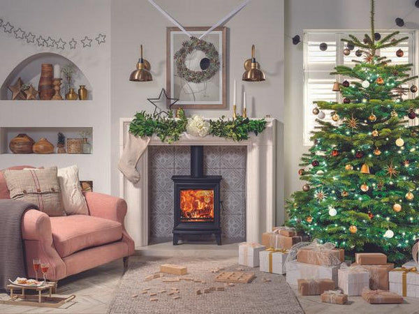 A living room with a fire decorated for Christmas
