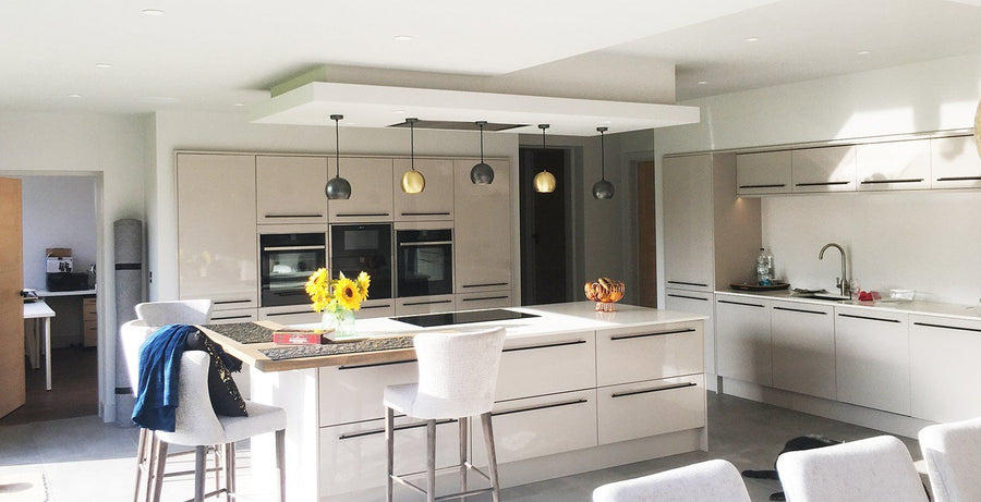 Open plan neutral kitchen interior with industrial lighting above kitchen island