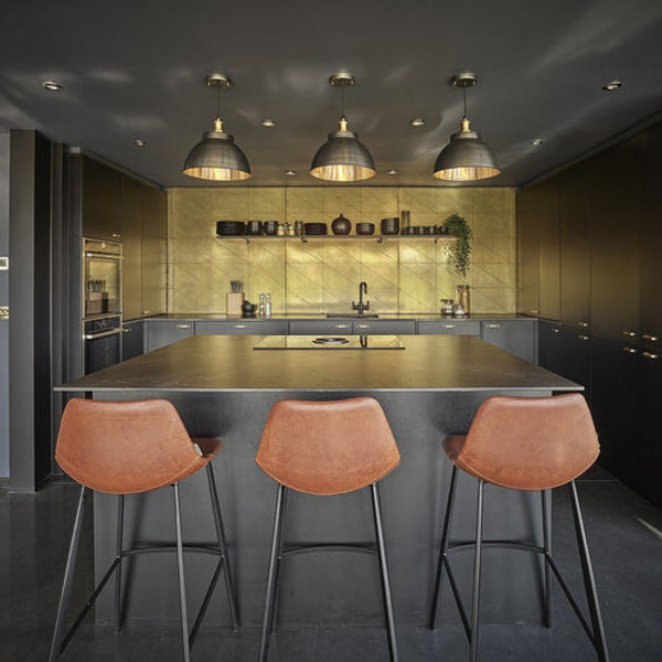 A trio of brass industrial pendant and brass lights over a kitchen island 
