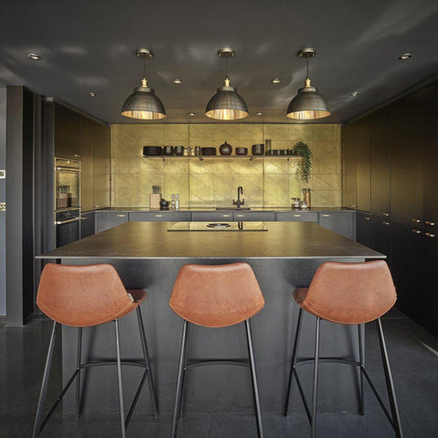 A trio of brass industrial pendant and brass lights over a kitchen island 