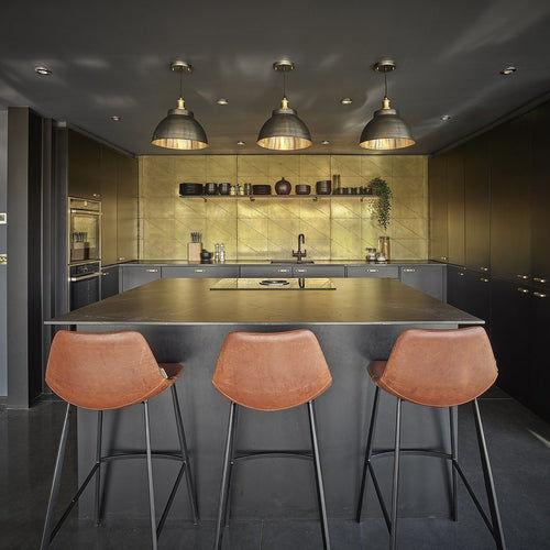 A trio of brass industrial pendant and brass lights over a kitchen island 