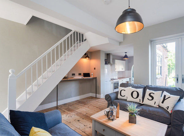 A living room with cushions on a sofa and industrial lighting by Industville