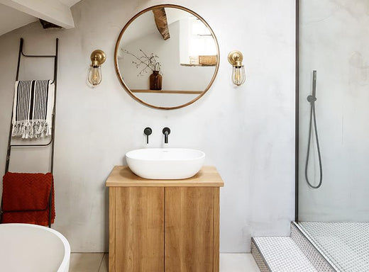 Nude bathroom interior with brass lights and oval mirror