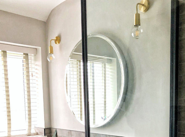 A natural-toned bathroom with stone wall and brass lights by Industville