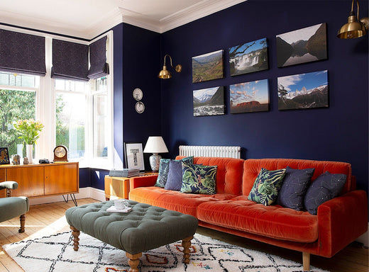 A contemporary living room with dark blue wall and brass lighting