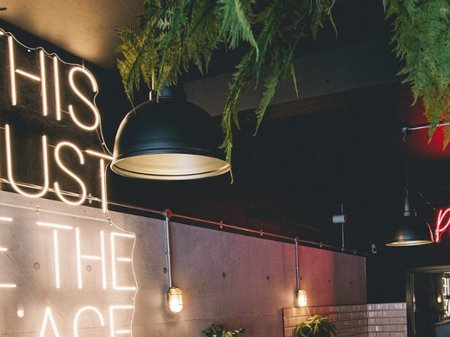 A large retro pendant lighting up a burger restaurant alongside neon signs