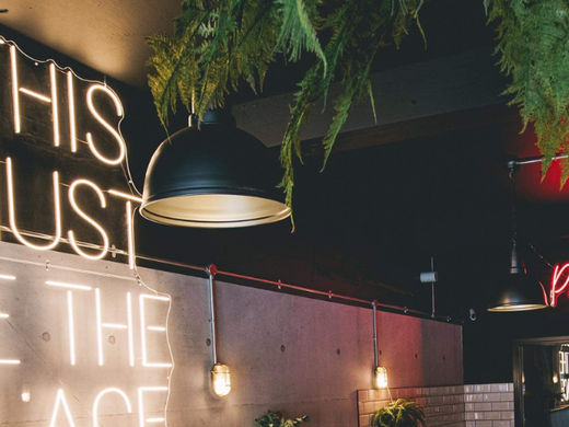 A large retro pendant lighting up a burger restaurant alongside neon signs
