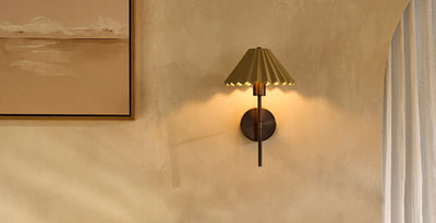 Ceramic hallway wall light with a pleated bronze shade, casting warm ambient lighting against a textured wall.