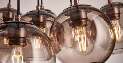 Close-up of smoked glass cluster pendant showcasing filament bulbs, part of the Cluster & Chandelier Lights collection.
