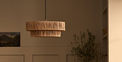 Farmhouse-style raffia pendant light with a layered shade, adding natural texture and warmth to a rustic interior.