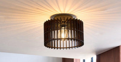 Low ceiling semi-flush mount light with a wooden cage design and exposed bulb, casting a warm patterned glow across the ceiling.