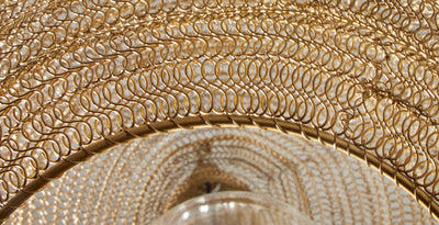 Close-up detail of brass wire cage light shade, highlighting the intricate looped metal design.