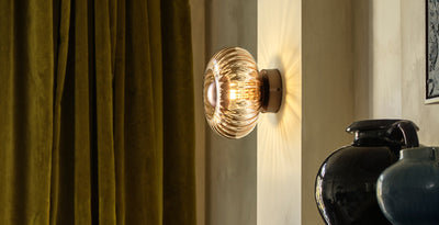 Elegant glass lighting wall sconce with ribbed detailing, casting a warm glow in a stylish living room setting.