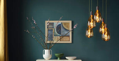 Cluster of amber LED decorative light bulbs with exposed filaments, creating a warm glow against a deep green wall.