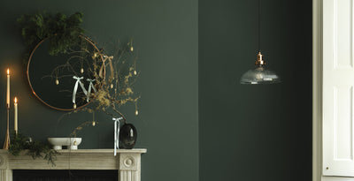 Stylish living room with a ribbed glass dome pendant light, festive greenery on the mantelpiece, and elegant decor, perfect for Christmas gift ideas.