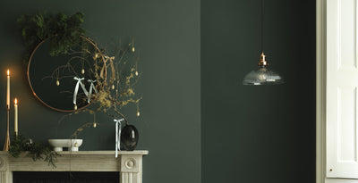 Stylish living room with a ribbed glass dome pendant light, festive greenery on the mantelpiece, and elegant decor, perfect for Christmas gift ideas.