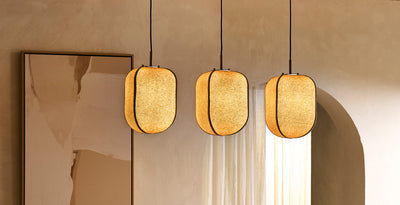 Trio of fabric pendant lights with rounded shades, casting a warm glow in a modern dining room setting.