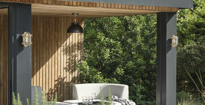 Outdoor seating area featuring brass bulkhead wall lights and a dome flush mount ceiling light, perfect for garden or patio lighting.