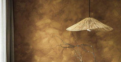 Raffia ceiling pendant light from the outlet collection, styled against a textured ochre wall for a rustic natural look.