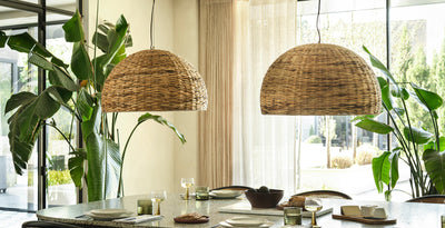 Dining room with two large dome-shaped sea grass pendant lights hanging above a modern table, styled with greenery and natural light.