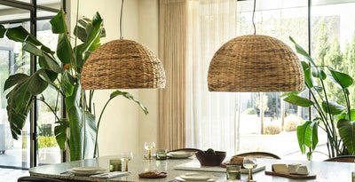 Dining room with two large dome-shaped sea grass pendant lights hanging above a modern table, styled with greenery and natural light.