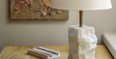 Stone table lamp with a raw marble base and white empire shade, adding a natural and sculptural touch to modern interiors.