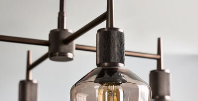 Close-up of a modern bronze and mocha chandelier with exposed filament bulb and industrial-style detailing.