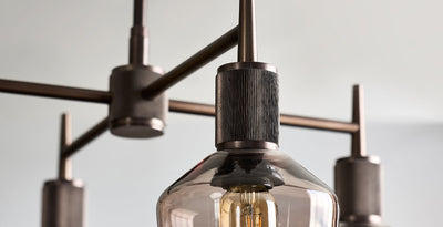 Close-up of a modern bronze and mocha chandelier with exposed filament bulb and industrial-style detailing.