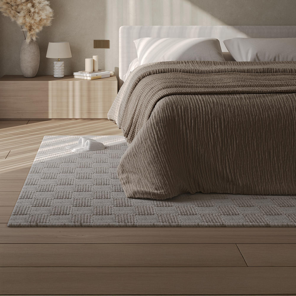 Ivory hand-woven wool rug, featuring a geometric pattern with the corner folded back to show the underside, on a floor background.