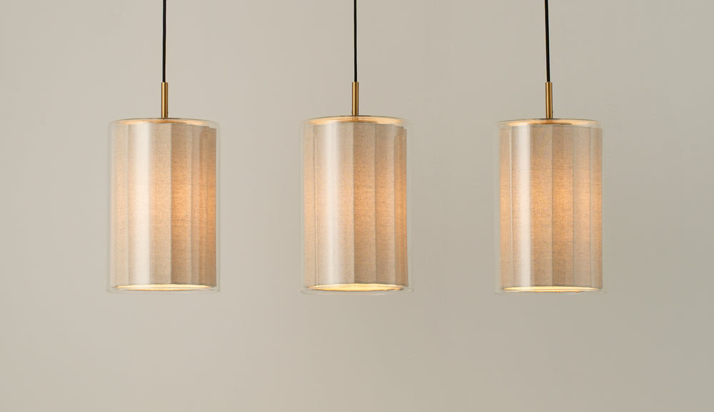 Bude Cylinder 3 Wire Cluster Pendant Light with Linen  and Clear Glass shades lit up, close up of the three shades 
