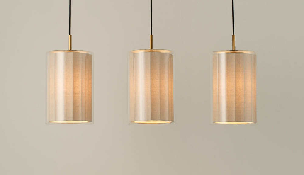 Bude Cylinder 3 Wire Cluster Pendant Light with Linen  and Clear Glass shades lit up, close up of the three shades 