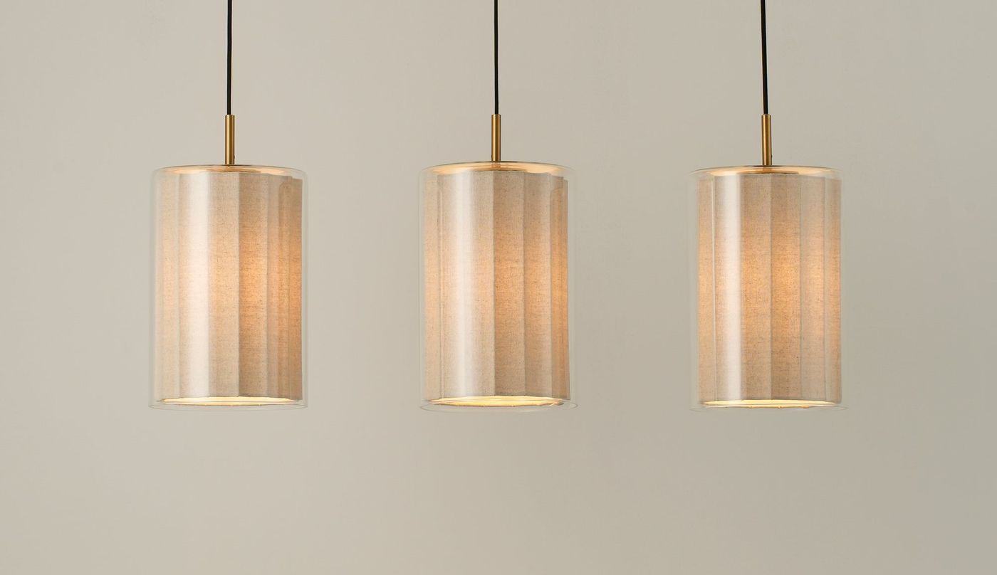 Bude Cylinder 3 Wire Cluster Pendant Light with Linen  and Clear Glass shades lit up, close up of the three shades 