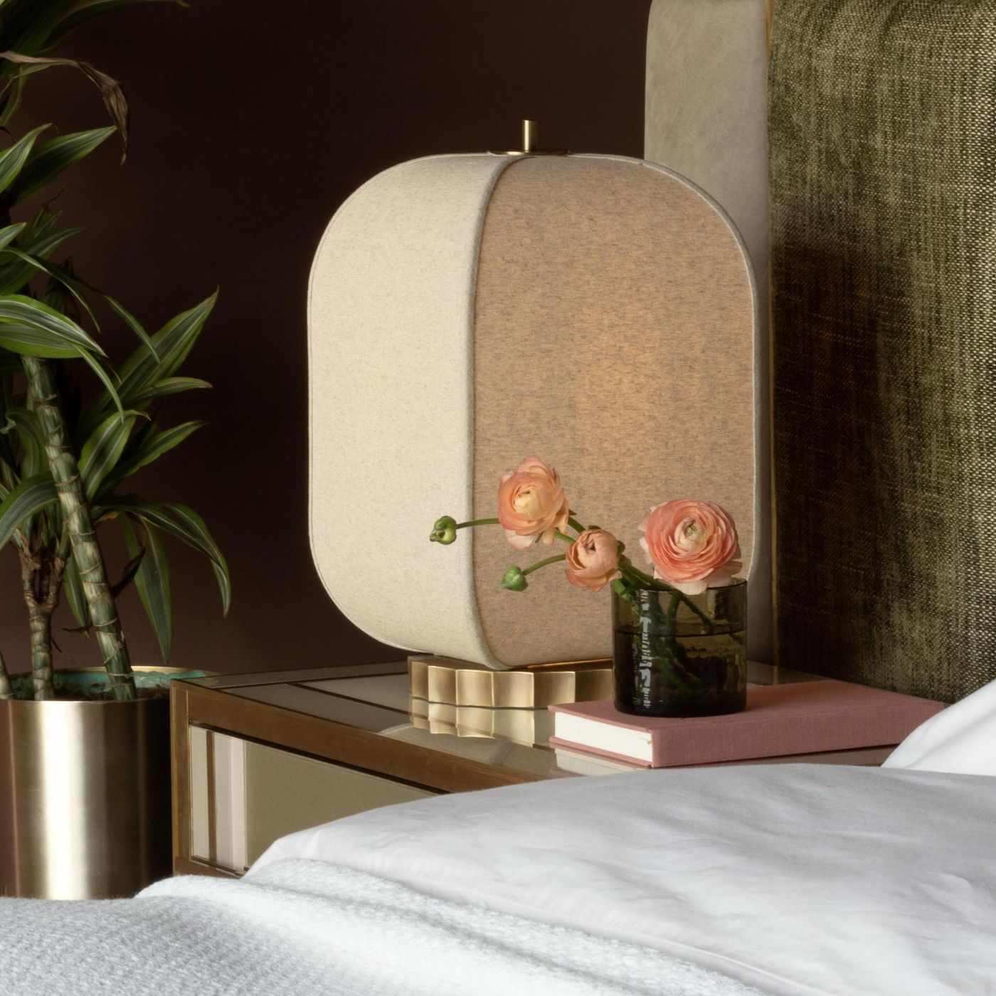 Bloxham Rectangular Table Lamp in Natural Fabric finish lit up next to a bed