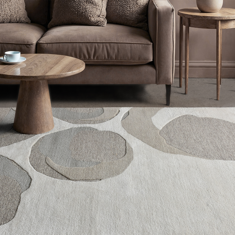 A hand-tufted wool rug with a beige and gray color scheme, showing the texture and quality of the wool.