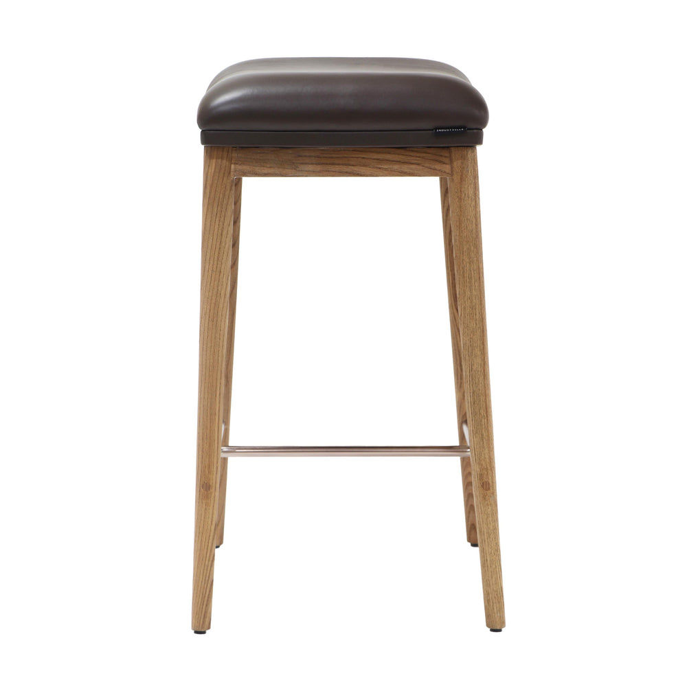 Rear view of a counter height stool showcasing natural ash wood legs, brown soft leather seat, and a brushed metal footrest.