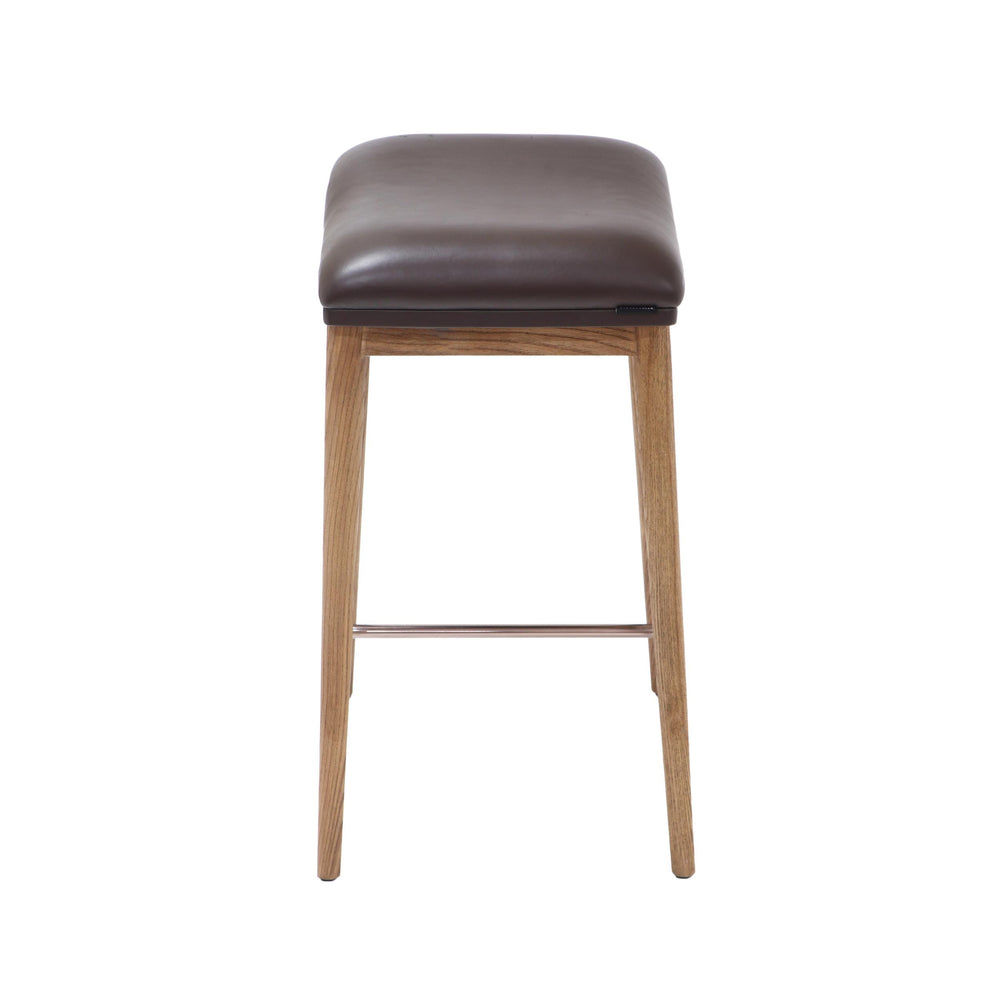 Side view of a counter height stool featuring natural ash wood legs, a brown soft leather seat, and a brushed metal footrest