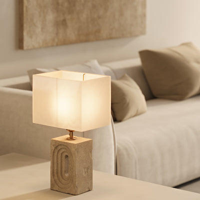 Natural travertine table lamp in rectangular shape on top of a white sideboard next to a sofa