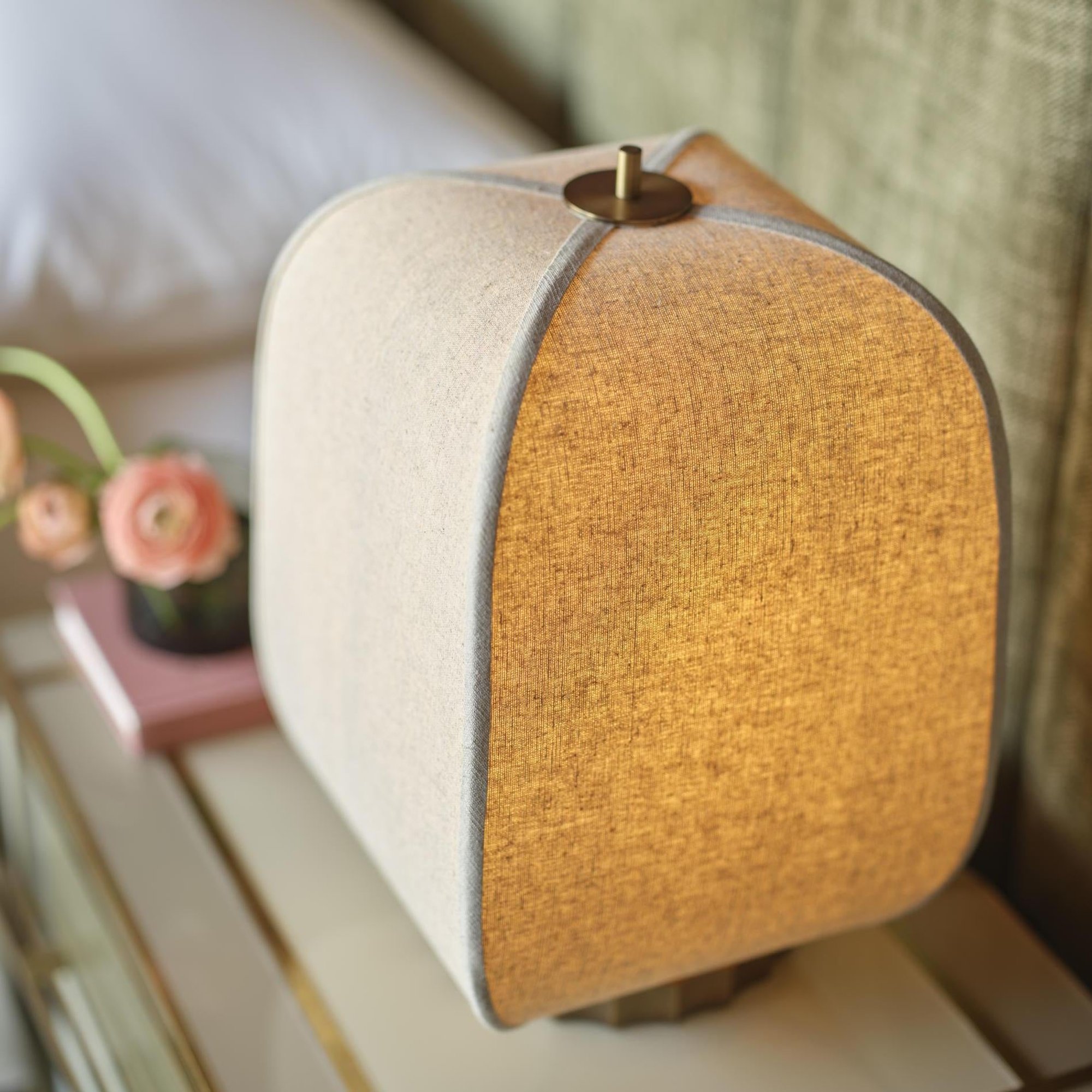 Bloxham Rectangular Table Lamp in Natural Fabric finish lit up next to a bed